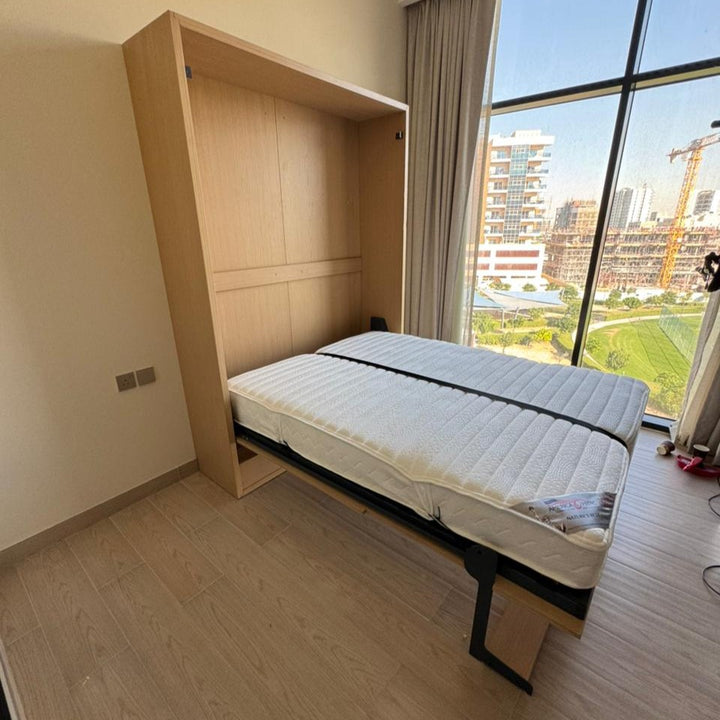 Wooden Murphy bed in a room with large windows showing a cityscape.